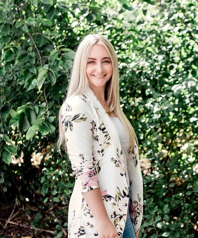 Cassandra Plant, RMT, smiling outdoors in front of greenery
