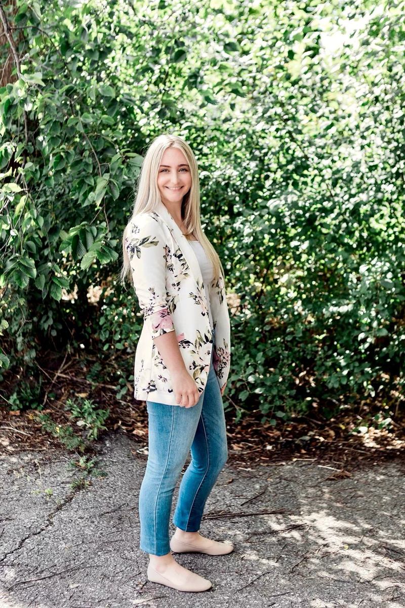 Portrait of Cassandra Plant, RMT, smiling outdoors in front of greenery